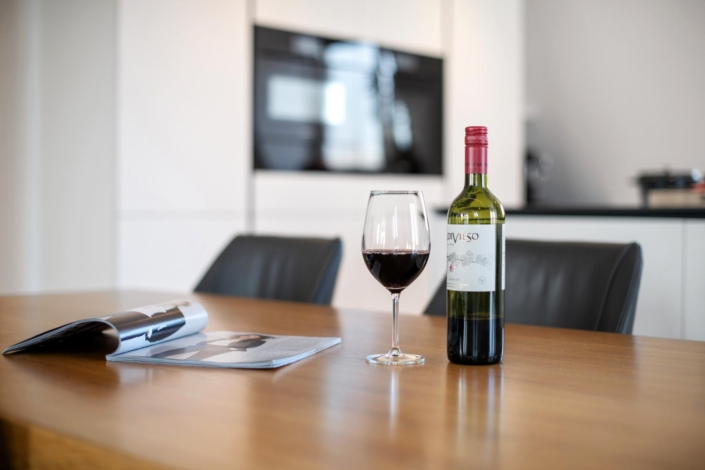 Fles en glas rode wijn op tafel in moderne keuken.