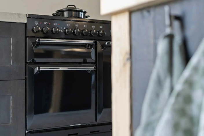 Detailfoto van zwarte oven en inductieplaat in een industriële keuken van VDB Wonen.